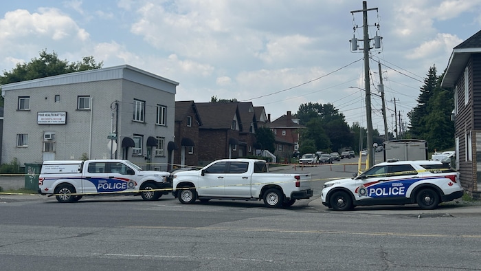 Des voitures de police barrent l'accès à une rue résidentielle.