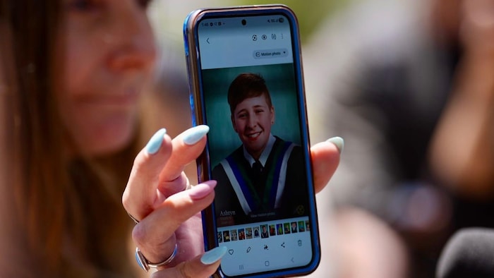 Une femme montre une photo sur son téléphone.