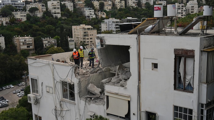 Les autorités israéliennes inspectent une maison endommagée à la suite d'une frappe de missiles iraniens à Haïfa, en Israël, le lundi 30 mars 2026.