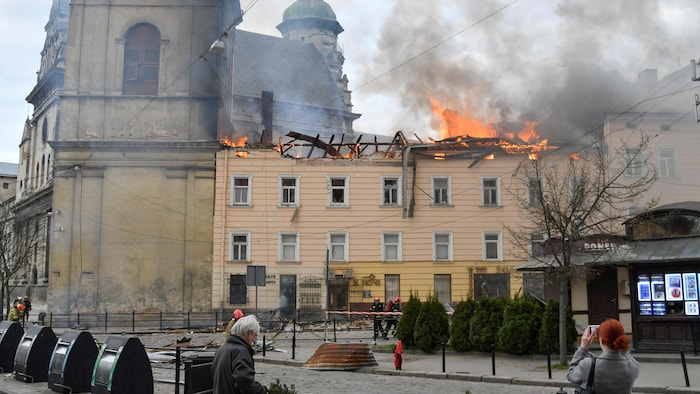 Des flammes sortent du toit d'un bâtiment. 