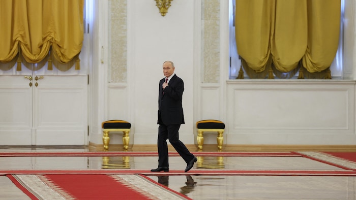 Vladimir Poutine marche seul dans une grande pièce.