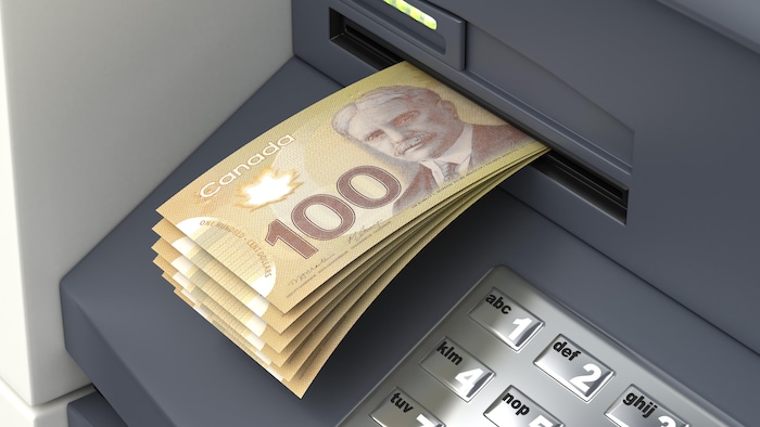 Des billets de banque sortent d'un guichet automatique.