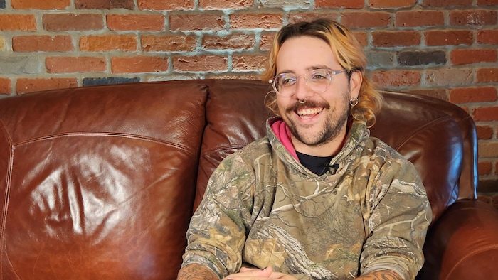 Sola Benoit Robillard, sur un sofa, sourit.