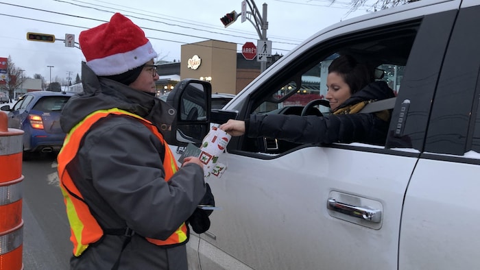 Une bénévole récolte le don d'une automobiliste de Saint-Félicien.