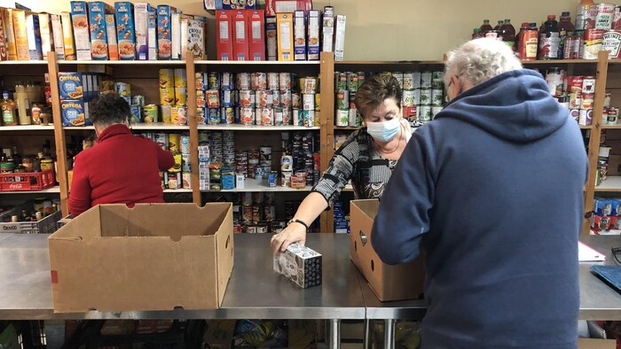 Des personnes remplissent des tablettes au comptoir alimentaire.