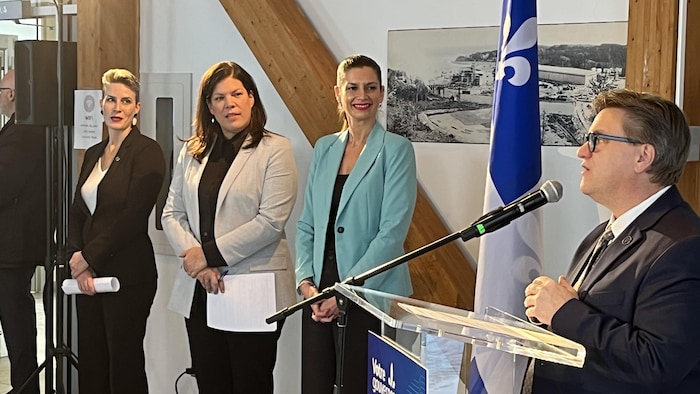 Karine Otis, Kateri Champagne Jourdain et Geneviève Guilbault écoutent attentivement Yves Montigny qui s'adresse au public en conférence de presse. 