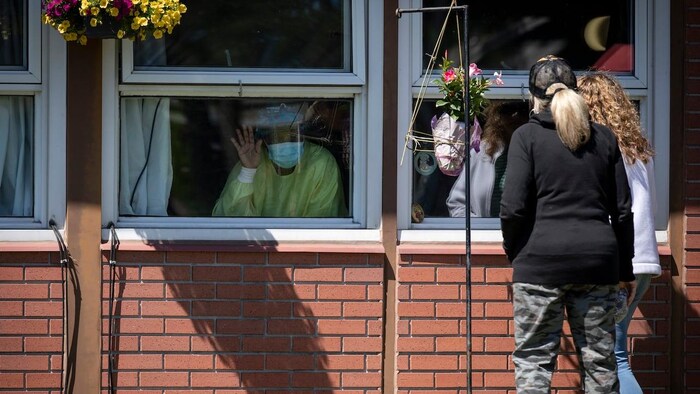 People inside a building look at people outside coming to visit them.