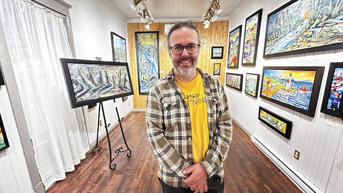 Portrait de Guillaume Gagnon devant plusieurs de ses toiles.