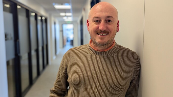 Guillaume Gonzalez pose dans le corridor de l'hôtel de ville en souriant. 