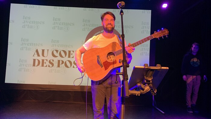 Un chanteur sourit avec une guitare dans ses mains.