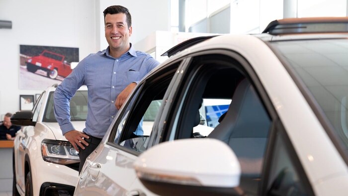 A man leans on a car.