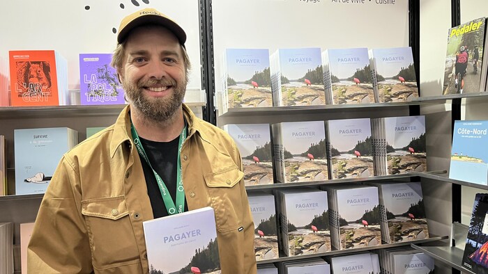 Guillaume Rivest avec son livre Pagayer dans un kiosque au Salon du livre à Val-d'Or.