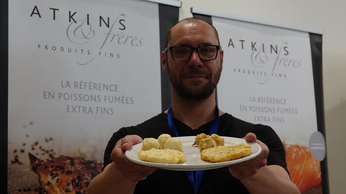 Un homme tient une assiette avec des boulettes de poisson.