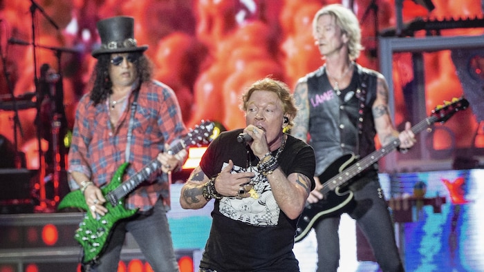 Axl Rose sur scène avec Slash et Duff McKagan derrière lui.