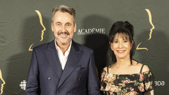 L'homme et la femme se tiennent par la main et sourient sur le tapis rouge. 