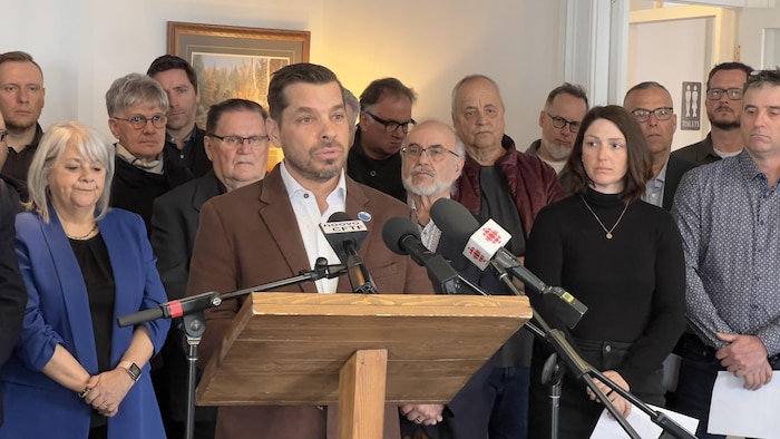Le préfet de la Haute-Gaspésie, Guy Bernatchez, au micro avec plusieurs personnes derrière lui.