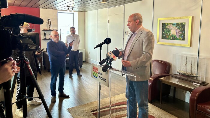 Guy Caron en conférence de presse devant un lutrin. 