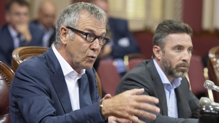 Deux personnes s'adressent aux élus lors d'une commission parlementaire.