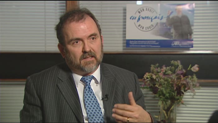 Guy Jourdain parle en faisant des gestes de la main.