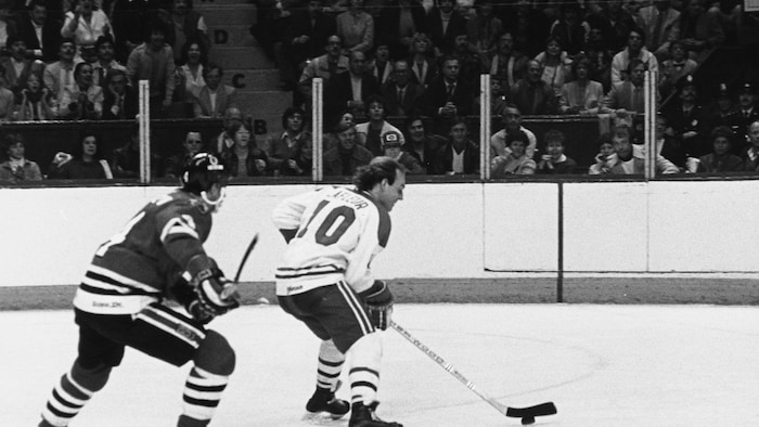Guy Lafleur avec la rondelle poursuivit par un joueur des Blackhawks.