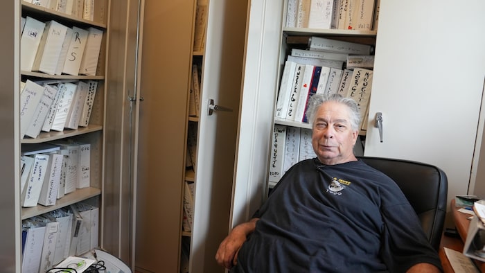 Un homme devant des cartables de journaux.