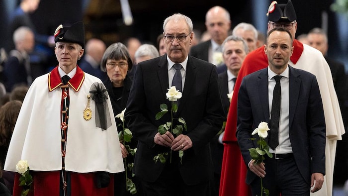 Deux hommes, le visage grave, marchent une rose à la main lors d'une cérémonie.