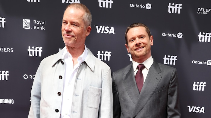 Deux hommes posent sur un tapis rouge.