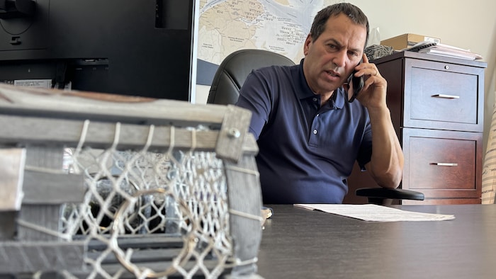 Guy Vigneault est à son bureau et parle au téléphone.