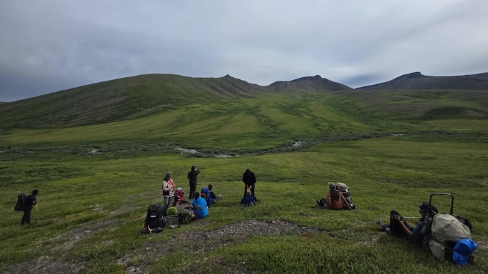 Une image des membres du groupe assis dans un paysage montagneux.