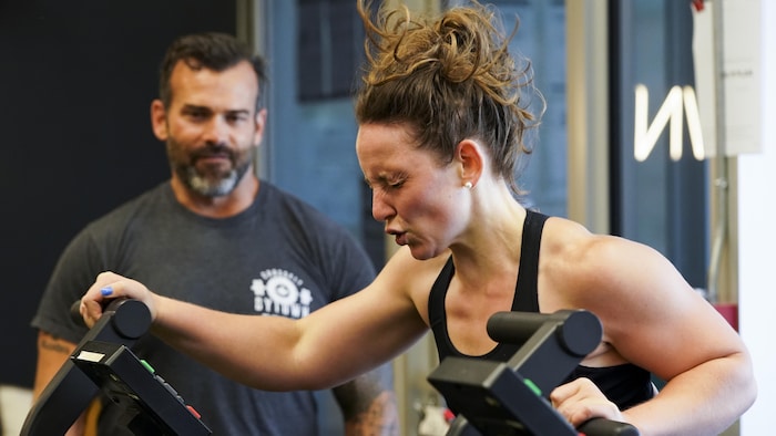 Un client regarde la propriétaire du Everett Sloan of Crossfit Bytown Lili Johanis qui s'entraîne.