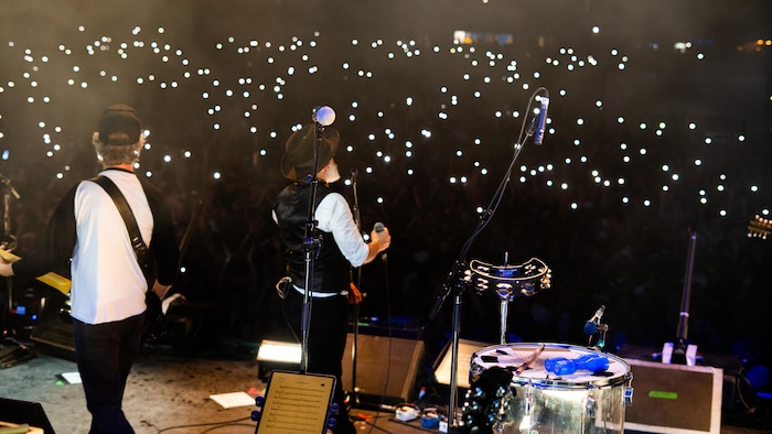 Une vue de la scène d'H2O le festival, avec JF Pauzé de dos, devant plusieurs téléphones cellulaires illuminés.