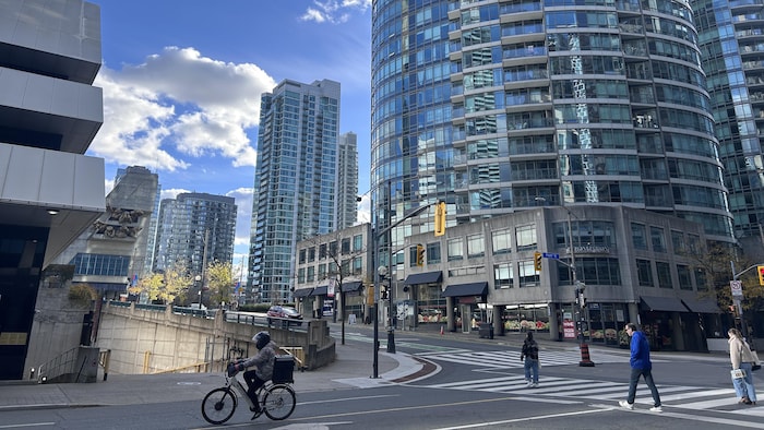 Des passants traversent la rue devant des immeubles de logements en copropriété à Toronto.