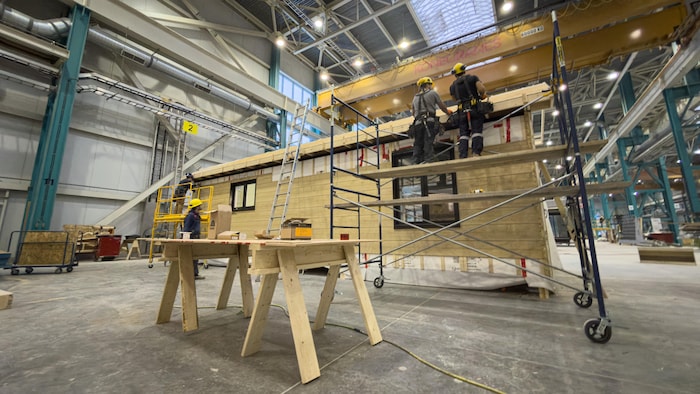 Des menuisiers travaillent à la construction d'une maison à l'intérieur d'une usine.
