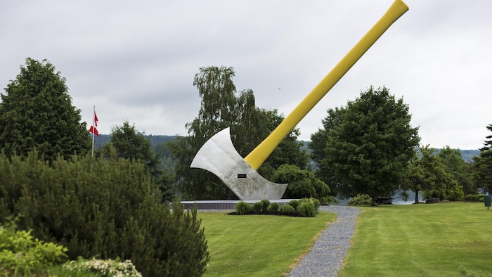 Une statue de hache de 15 mètres de haut plantée dans un champ.