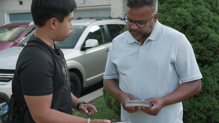 Ahsanul Hafiz et le jeune bénévole regardent la liste sur le téléphone intelligent de celui-ci.
