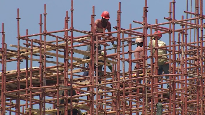 En Haïti, des hommes s'affairent sur les échafaudages d'un chantier de construction.