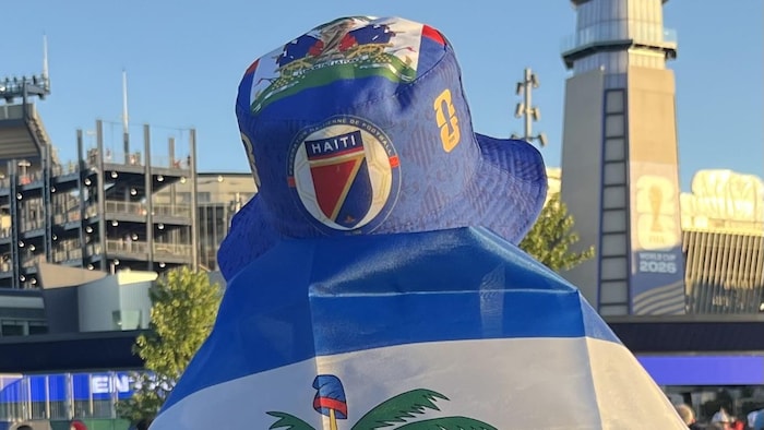 Il porte un chapeau et un drapeau sur son dos.