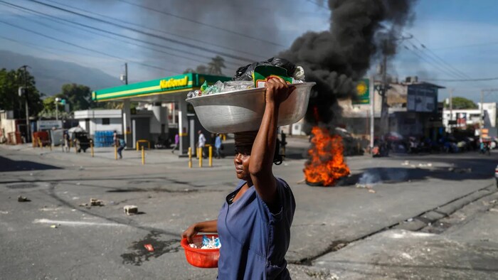 A street vendor walks past tires set fire at a closed gas station as part of a protest against fuel shortages in Port-au-Prince on Thursday.
