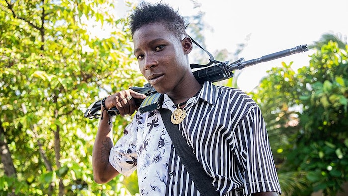 A young man holding a gun poses for the photo.