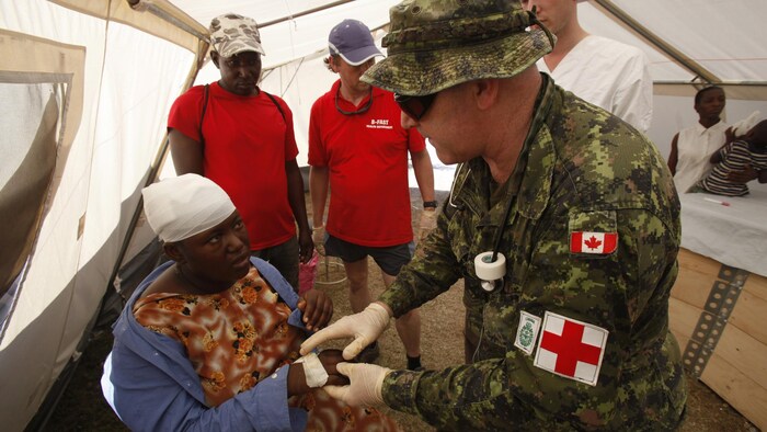ممرض من القوات المسلحة الكندية يعالج امرأة في بور أو برينس في أعقاب الزلزال الذي ضرب العاصمة الهايتية في كانون الثاني (يناير) 2010.