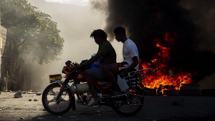 Deux hommes en moto près d'un incendie.