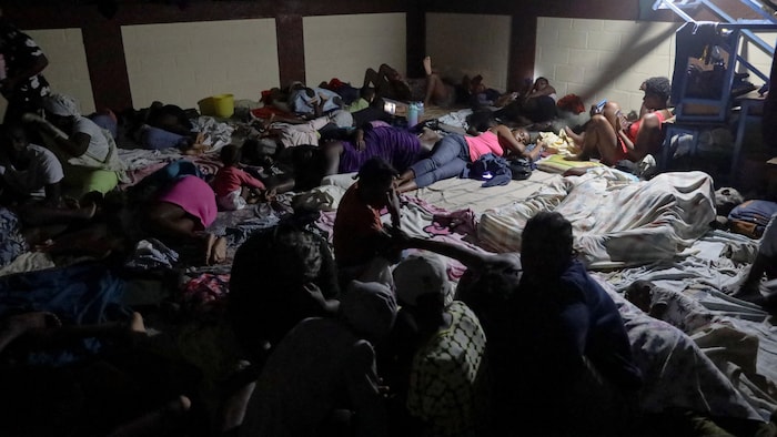 Des gens dorment au sol dans un refuge d'urgence.