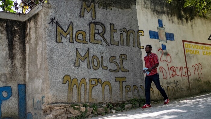 Un homme passe devant un graffiti près de la résidence où le président Jovenel Moïse a été assassiné à Port-au-Prince.