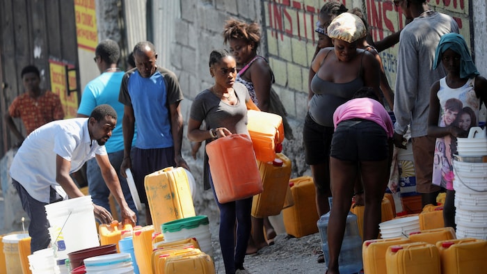 Des personnes se servent de l'eau dans des seaux et des conteneurs pour éviter la famine.