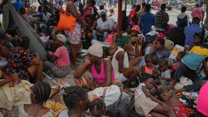 Lots of people crowded together are sitting on the ground. 