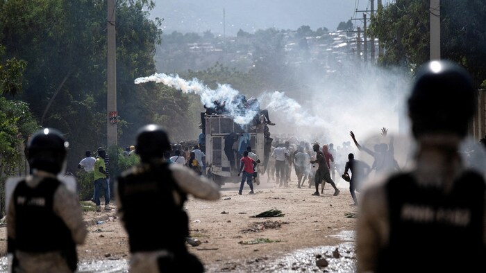 Des agents de la police nationale haïtienne déploient des gaz lacrymogènes lors d'une manifestation de la population.