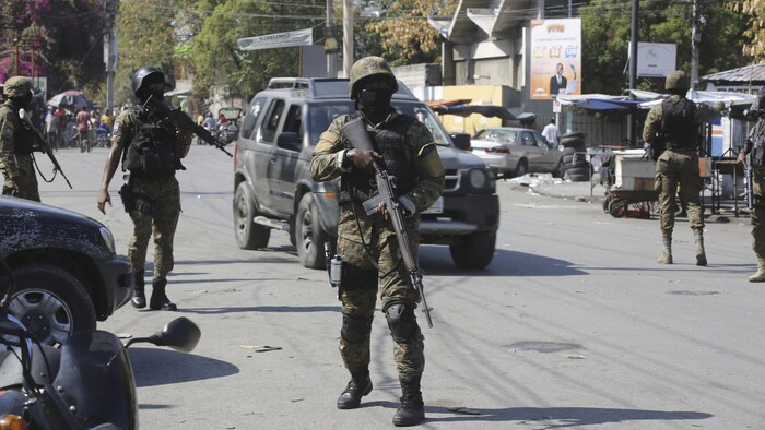 Des hommes armés et cagoulés sont postés dans une rue de Port-au-Prince.