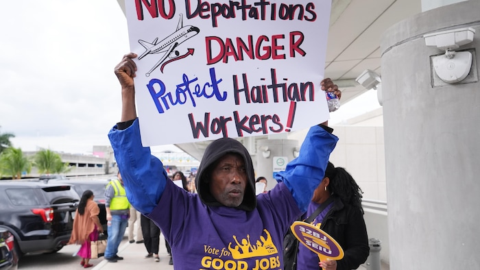 Un homme brandit une pancarte en faveur du statut de protection temporaire des migrants haïtiens aux États-Unis.