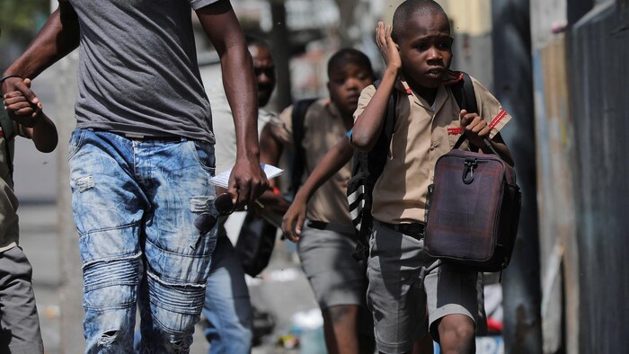 Un enfant se couvre les oreilles en raison des violences à Port-au-Prince.