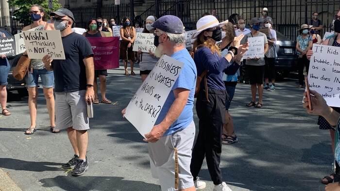 Des gens manifestent devant l'édifice de l'Assemblée législative.